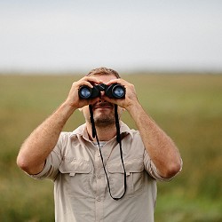 man looking through binoculars (image: StockSnap / pixabay)